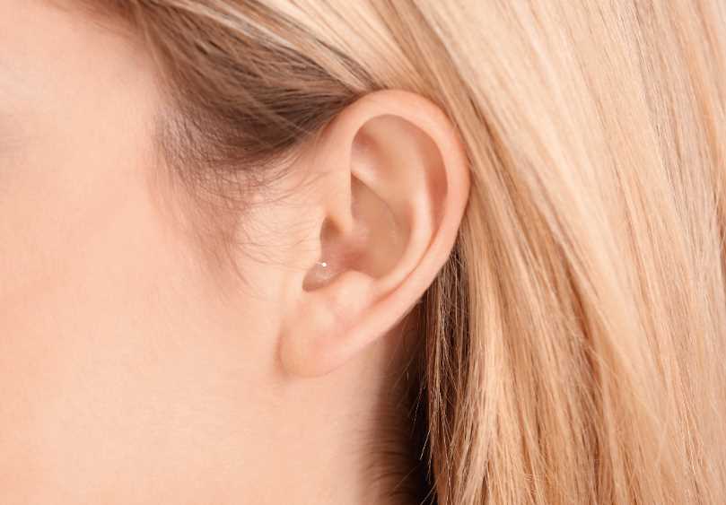 Im-Ohr-Hörgerät, dass kaum zu sehen ist. Nahaufnahme vom Ohr