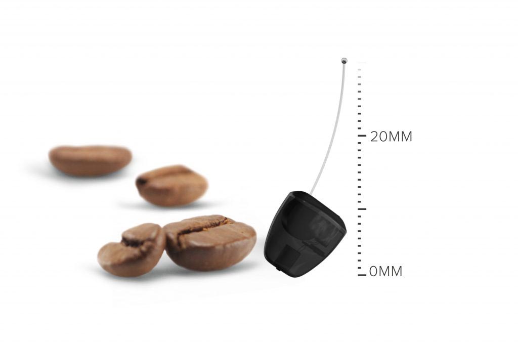 Hier wird ein optischer Größenvergleich von Kaffeebohnen und einem Liberty-Hörgerät gezeigt, daneben eine Größenskala in mm